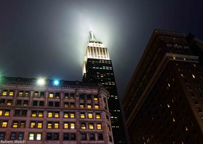 "misty night image of Empire State building lighting the sky"