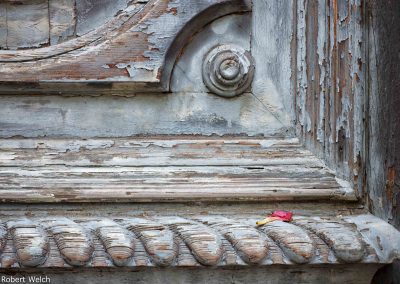 "closeup photo of old door in Puerto Rico with peeling white paint and flower petal"