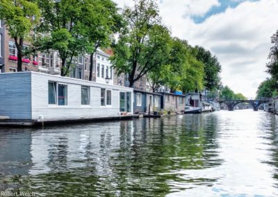 houseboats line an Amsterdam canal in this summer scene