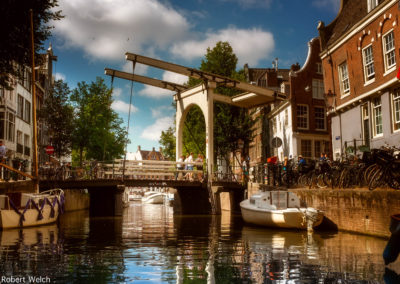 "Amsterdam canal and drawbridge with boats and warm sunshine tones"