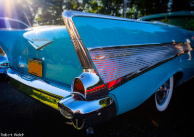 "rear quarter view of a turquoise '57 Chevy with sunrays shining down"