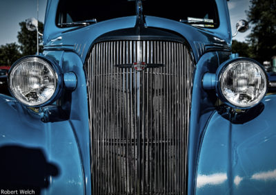 "closeup of grille and headlights on old blue chevy pickup truck"