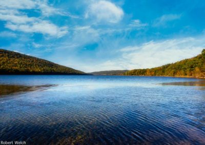 "Canadice Lake in fall under blue sky and wispy clouds"