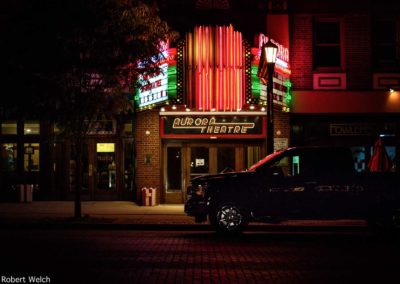 street view of the Aurora Theatre at night with pickup truck in front
