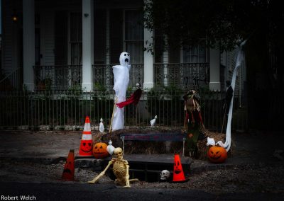 "halloween scene at street drain in New Orleans with skeleton, ghost and pumpkins"