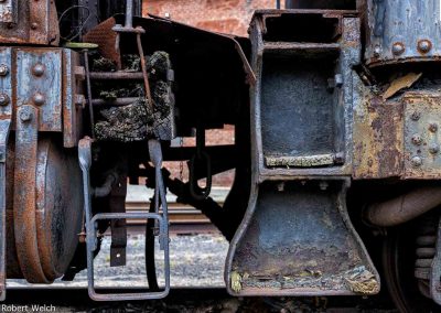 "detail photo of rotted wood and rust on an antique rail plow engine"